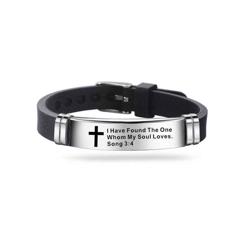 Black leather bracelet with silver tag featuring a cross and Bible verse on a white background