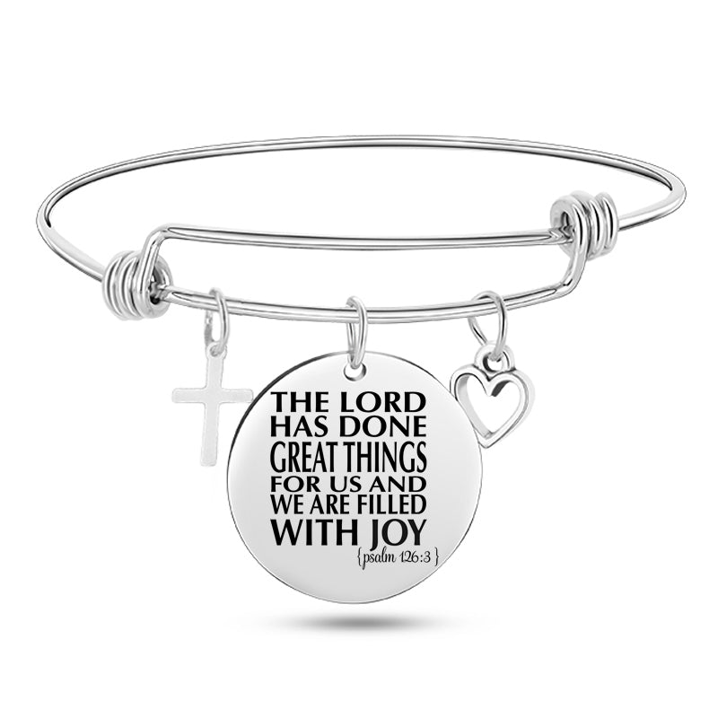 Silver bracelet with a circular charm featuring a religious quote on a white background