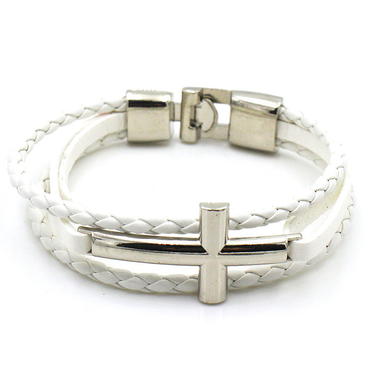 White braided leather bracelet with silver clasp and cross charm on a white background