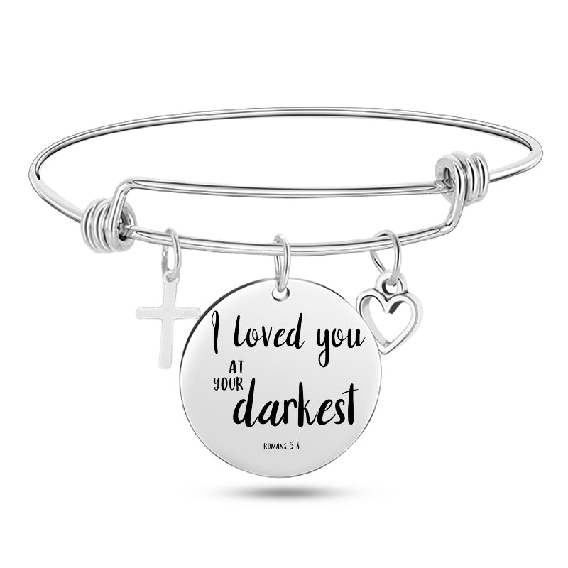 Silver bracelet with a round charm displaying 'I loved you at your darkest' on a white background