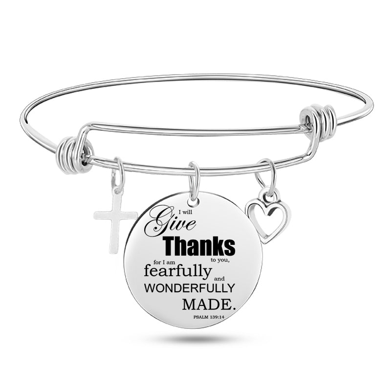 Silver bracelet with circular charm featuring a quote and religious symbols on a white background