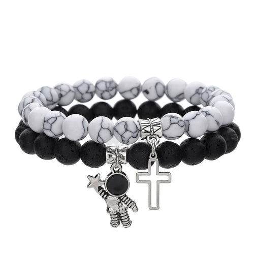 Stack of black and white beaded bracelets with charms on a white background