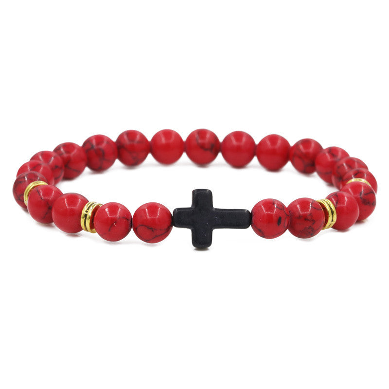 Red beaded bracelet with a black cross charm on a white background