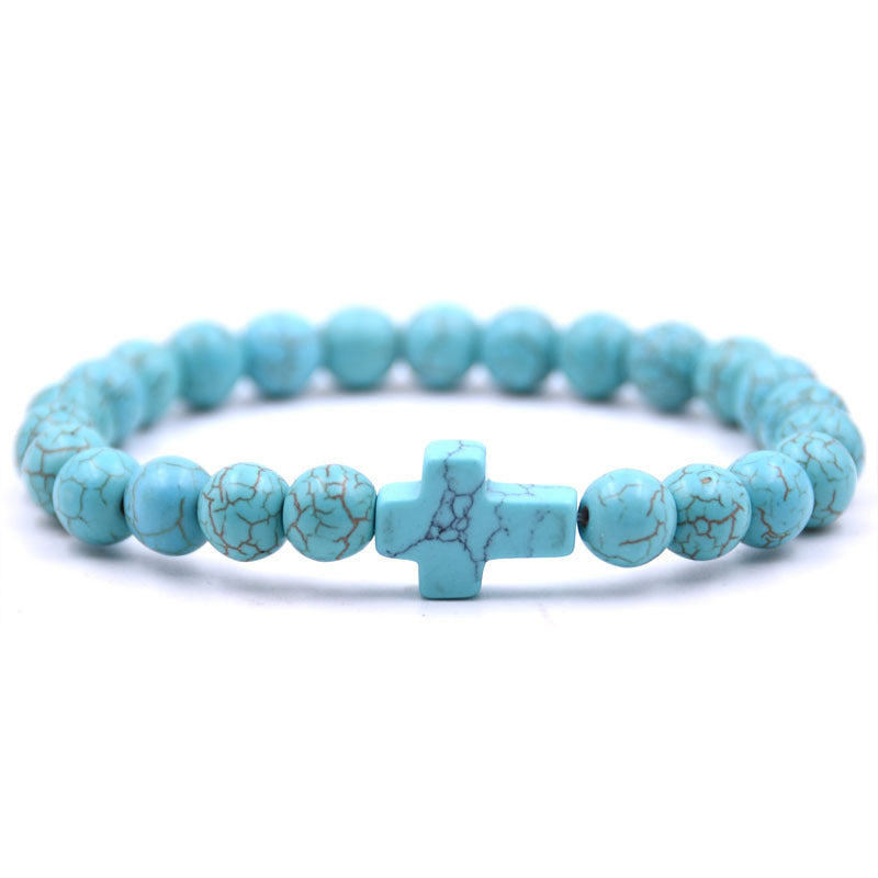 Turquoise beaded bracelet with a cross charm on a white background