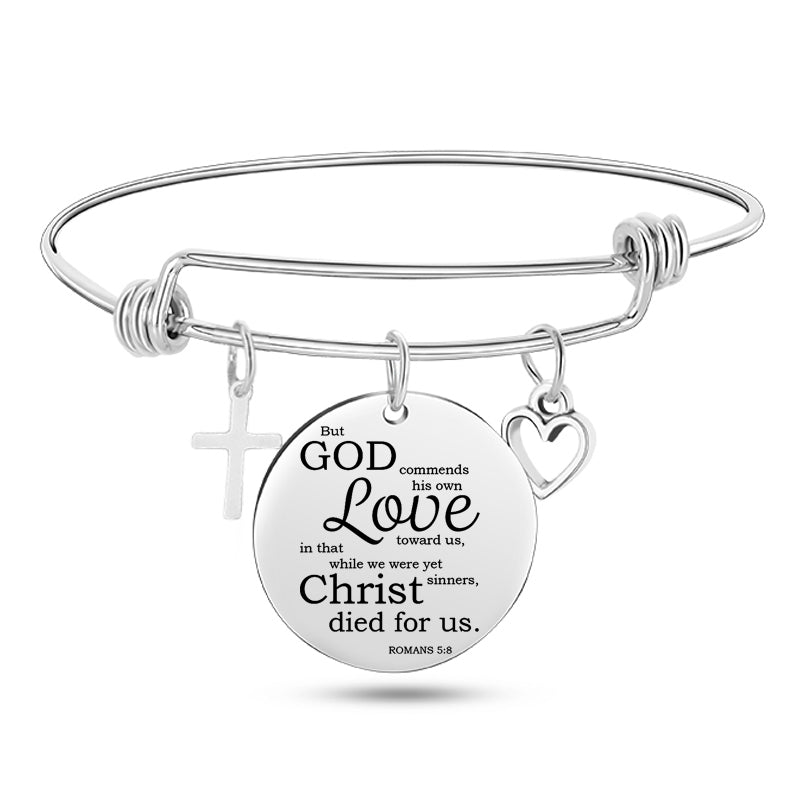 Silver bracelet with a circular charm featuring text and religious symbols on a white background