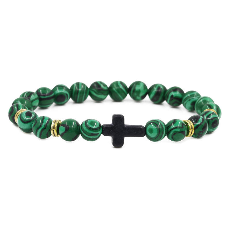 Green beaded bracelet with a black cross on a white background
